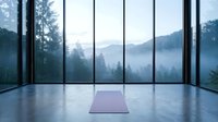 Yoga mat on polished floor in modern minimalist studio with panoramic windows overlooking misty forest mountains and evergreen trees at dawn.