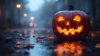 Glowing carved pumpkin with classic jack o'lantern face illuminated from within on dark autumn ground with bokeh lights and fallen leaves creating spooky Halloween atmosphere.