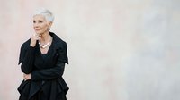 Elegant senior woman with short white hair wearing black blazer and trousers, posing confidently against neutral background. Suitable for business, lifestyle, and corporate design projects.