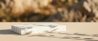 Marble stone podium with shadow on beige surface for product display and cosmetic branding mockup.