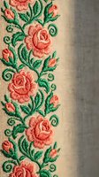 Embroidered coral roses with green leaves on beige fabric creating decorative floral border pattern for textile design and traditional needlework crafts.