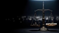 Ornate bronze scales of justice on dark background with dramatic lighting for legal and law firm presentations.