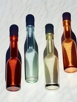 Colorful glass bottles casting long shadows on white background. Minimalist composition with amber, blue and green transparent vessels creates artistic pattern.