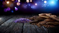 Dark chocolate pieces and lavender flowers on rustic wooden table with magical bokeh lights background creating romantic spa atmosphere.