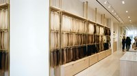 Modern retail interior with wooden fabric sample display wall showcasing textile swatches in organized rows for interior design showroom or store.