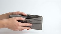 Female hands holding open empty gray leather wallet showing multiple card slots and compartments on white background.
