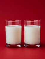 Two glasses of fresh white milk on vibrant red background for dairy products advertising and healthy nutrition campaigns.