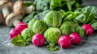 Fresh Brussels sprouts and bright pink radishes with green leaves on dark concrete background, healthy organic vegetables for seasonal cooking.