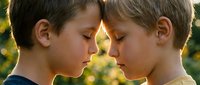 Two young Caucasian boys touching foreheads in a tender moment of sibling bond, soft natural bokeh background, warm golden light.
