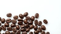 Roasted coffee beans scattered on white background, aromatic brown seeds for brewing espresso, cappuccino and other hot beverages in cafes and restaurants.
