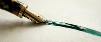 Fountain pen with gold nib leaking green ink on white paper, representing writing, creativity, and artistic expression for design and editorial projects.