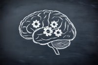 Chalk drawing of human brain with gear mechanisms representing cognitive processes and mental function on dark blackboard background.