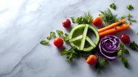 Fresh vegetables arranged in peace sign shape with cucumber, purple cabbage, carrots, cherry tomatoes and herbs on marble background. Food art concept for healthy eating.