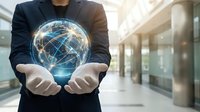 Professional businessman holding glowing digital globe with network connections in modern office corridor representing global business technology solutions.