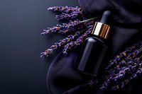 Dark glass bottle with gold cap surrounded by fresh purple lavender sprigs on black silk fabric, creating luxurious spa and aromatherapy composition.