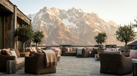 Luxury outdoor lounge area with wicker furniture and mountain backdrop, perfect for resort, hospitality, and lifestyle design projects.