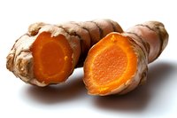 Fresh turmeric root sliced to reveal vibrant orange flesh against white background, showing natural organic spice ingredient for cooking and wellness.
