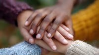 Close up view of caring hands holding each other in comfort and support, showing empathy and connection between people wearing warm knitted sweaters.