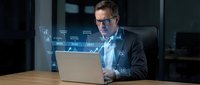 Professional businessman analyzing financial data on laptop with holographic interface display in modern office environment for business technology presentations.