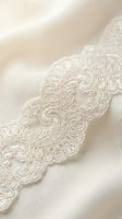 Ornate ivory lace trim with intricate embroidered scrollwork and floral details on cream fabric. Perfect for wedding dress embellishment, bridal wear, and luxury textile design projects.