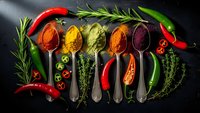 Colorful spices and herbs in vintage spoons with fresh chili peppers and rosemary on dark background for culinary cooking and seasoning recipes.