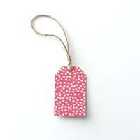 Pink gift tag with white heart pattern and rustic twine string on white isolated background, ready for Valentine's Day, wedding or romantic design projects.