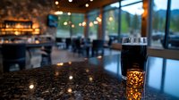 Dark craft beer glass on bar counter with blurred restaurant interior, ambient lighting and bokeh effects creating cozy evening atmosphere.