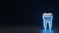 Glowing transparent tooth with internal structure on dark blue background for dental healthcare and medical presentations.
