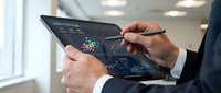 Professional businessman analyzing data analytics dashboard on tablet device with interactive charts and graphs in modern office environment.