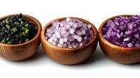 Three wooden bowls filled with different types of chopped onions including black, white and purple varieties arranged in row on white background for cooking.