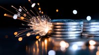 Glowing sparkler next to stacked silver coins with bokeh light effects on dark background, representing financial growth and investment success.
