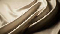 Smooth beige fabric with soft folds and flowing curves, creating an elegant abstract composition. Suitable for textile, fashion, and design backgrounds.