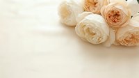 Soft cream and peach roses arranged on neutral beige background with copy space for romantic wedding invitations, greeting cards, and feminine branding projects.