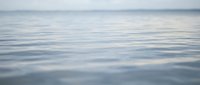 Calm ocean water surface with gentle ripples reflecting cloudy sky. Peaceful seascape background for meditation, wellness and tranquil nature concepts.