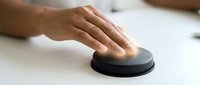 Hand touching black wireless computer mouse on white desk surface for technology and office work concepts.