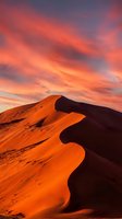 Dramatic desert sand dunes illuminated by vibrant orange and red sunset sky with deep shadows, showcasing natural landscape and atmospheric lighting for travel and nature projects.