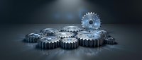 Metallic industrial gears and cogs machinery components on dark surface for engineering manufacturing technology automation concepts.