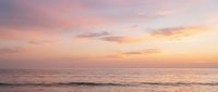 Serene ocean horizon at sunset with soft pink and golden sky reflecting on calm water, ideal for travel and nature backgrounds.