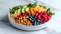 Fresh fruit and nuts bowl with berries, cucumber, cantaloupe, almonds and granola arranged in colorful sections on marble surface, healthy breakfast concept.
