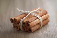 Bundle of aromatic cinnamon sticks tied with natural twine rope on wooden surface for cooking baking spices seasoning culinary ingredients kitchen decor.