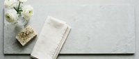 Elegant white ranunculus flowers with natural soap and linen towel on textured stone surface for spa wellness and organic skincare product display.