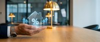 Businessman hand holding holographic house with percentage symbol representing mortgage rates, real estate investment and property financing concepts.