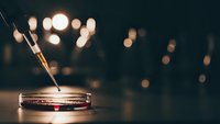 Burning incense stick in metal holder with warm bokeh lights creating peaceful meditation atmosphere for relaxation and mindfulness practices.