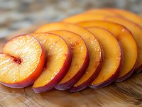 Fresh ripe peach slices arranged in row on wooden cutting board, juicy fruit with red skin and golden flesh, macro food photography.