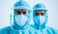 Healthcare workers in protective equipment with face shields and masks during pandemic, representing medical safety protocols and frontline response.
