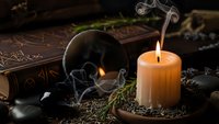 Mystical witchcraft altar with burning candle, crystal ball, ancient spell book and magical herbs for occult rituals and esoteric practices.