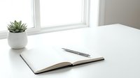 Minimalist workspace with open notebook and pen on clean white desk near bright window with small succulent plant for productivity and planning.