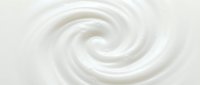 Smooth white cream swirl texture with soft spiral motion, suitable for cosmetics, skincare, and beauty product backgrounds.