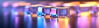 Transparent ice cubes with colorful reflections on glossy surface, creating vibrant bokeh effect in purple and orange tones.