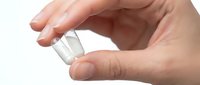 Hand holding clear plastic contact lens on fingertip for vision correction and eye care routine on white background.